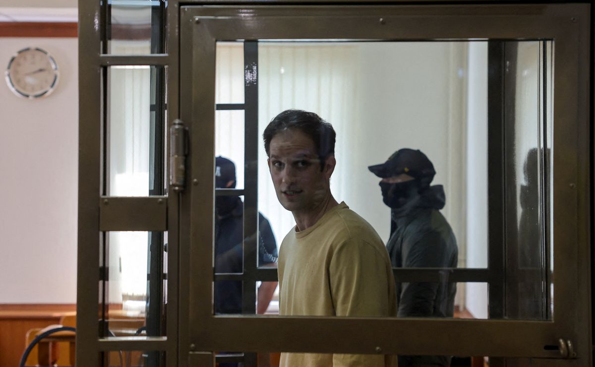 Wall Street Journal reporter Evan Gershkovich stands behind a glass wall of an enclosure for defendants before a court hearing 