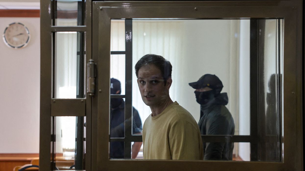 Wall Street Journal reporter Evan Gershkovich stands behind a glass wall of an enclosure for defendants before a court hearing