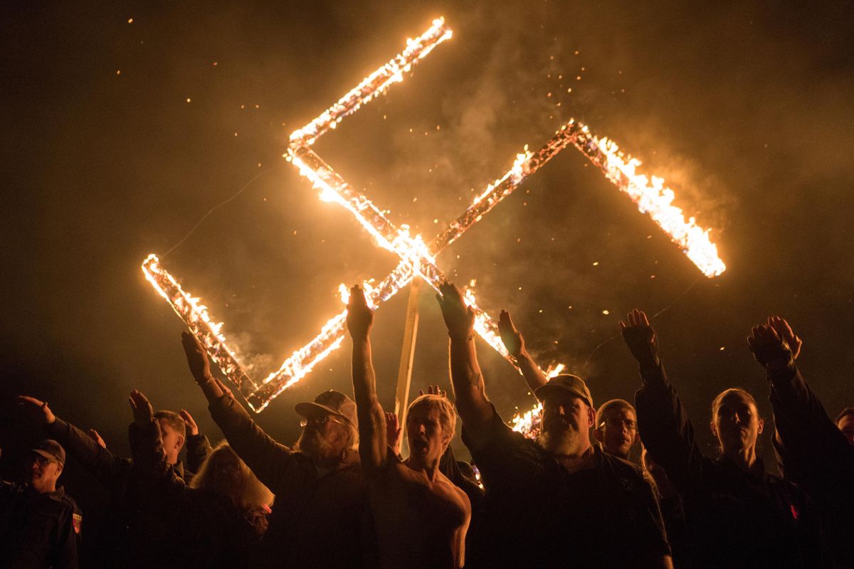 White nationalists give Nazi salutes while taking part in a swastika burning at an undisclosed location in the US state of Georgia.