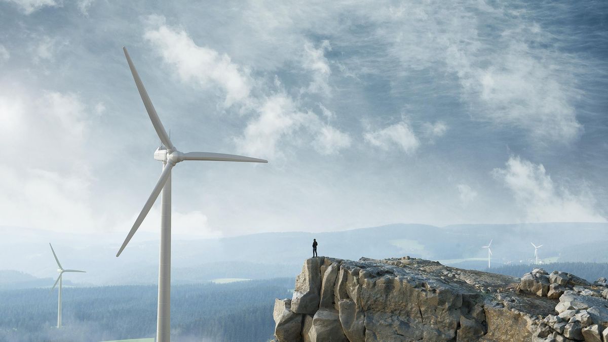Wind turbines with a cliff and mountains in the background. 