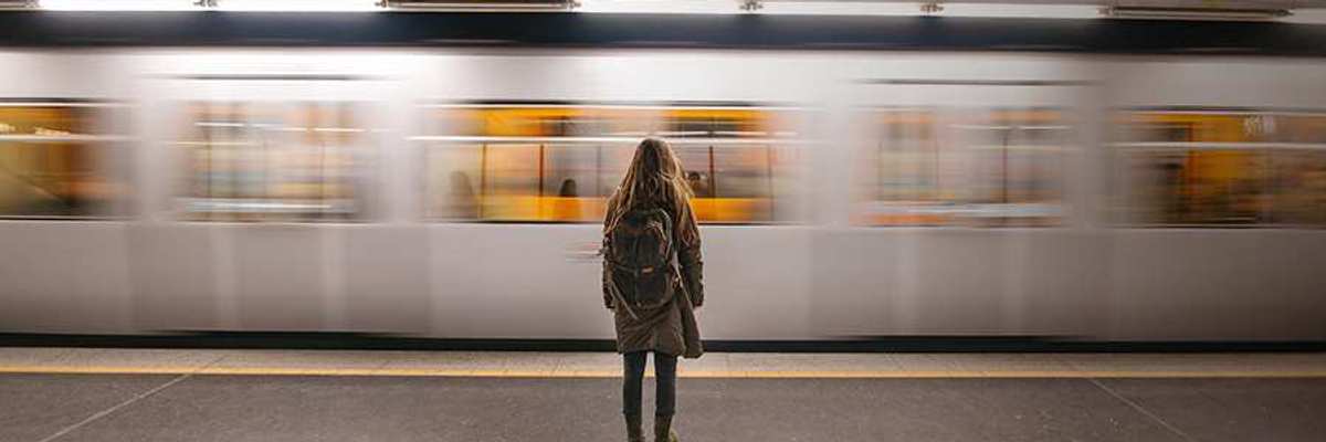 Woman at the train station as a train zooms past her