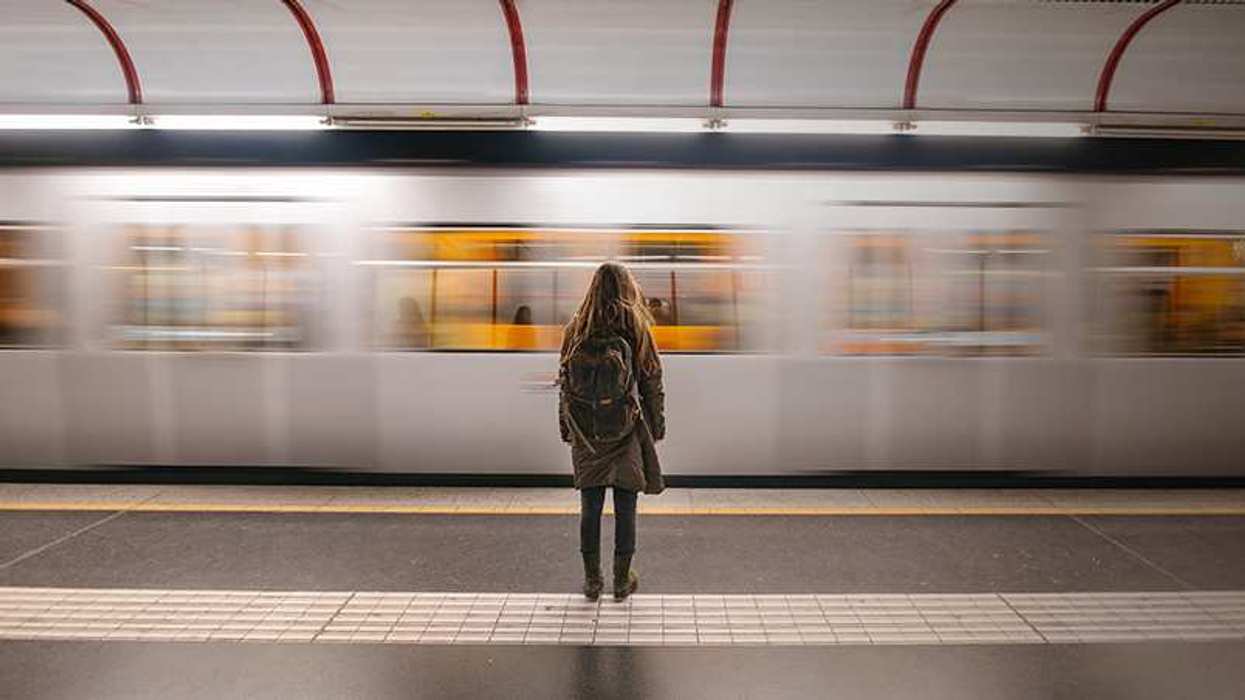 Woman at the train station as a train zooms past her