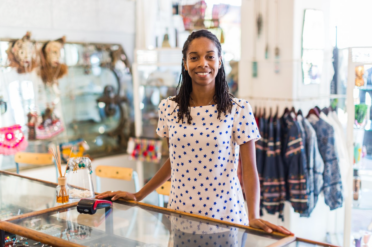 Woman in a white t-shirt with blue stars smiling at a counter in a retail shop