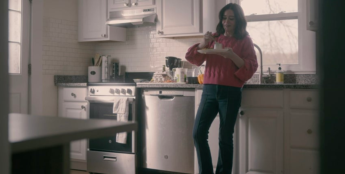 Woman standing in a kitchen and eating cake