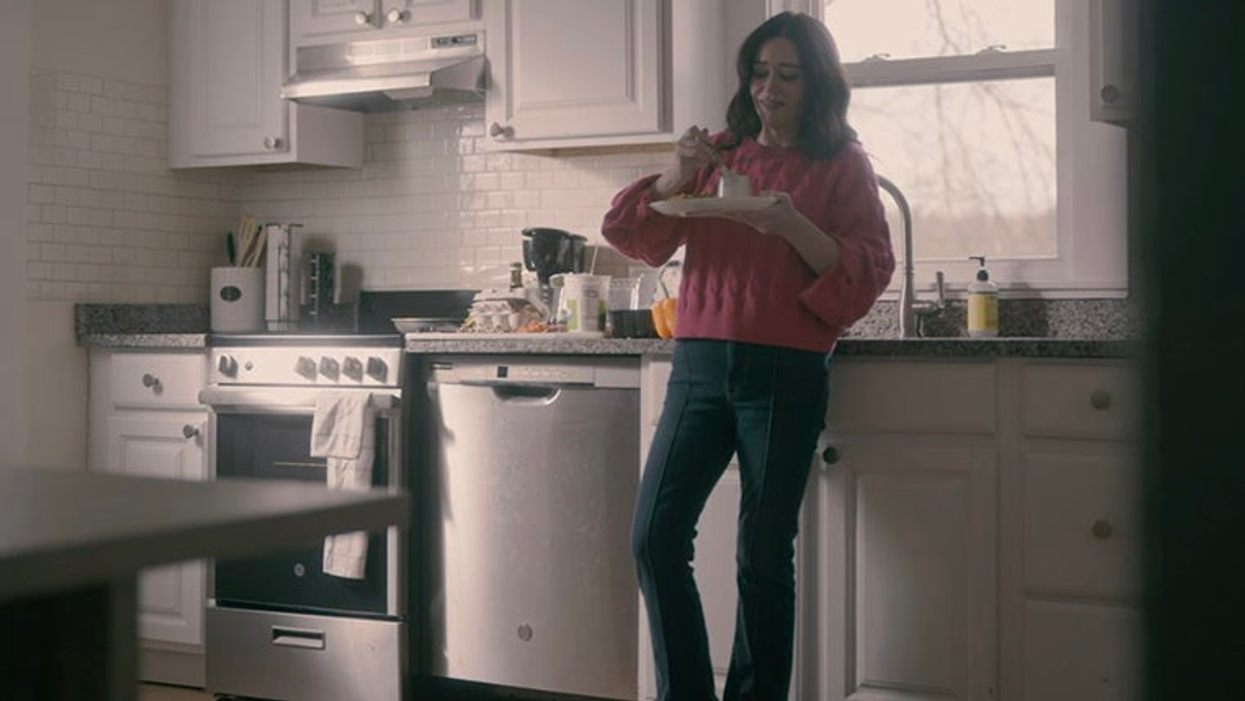 Woman standing in a kitchen and eating cake