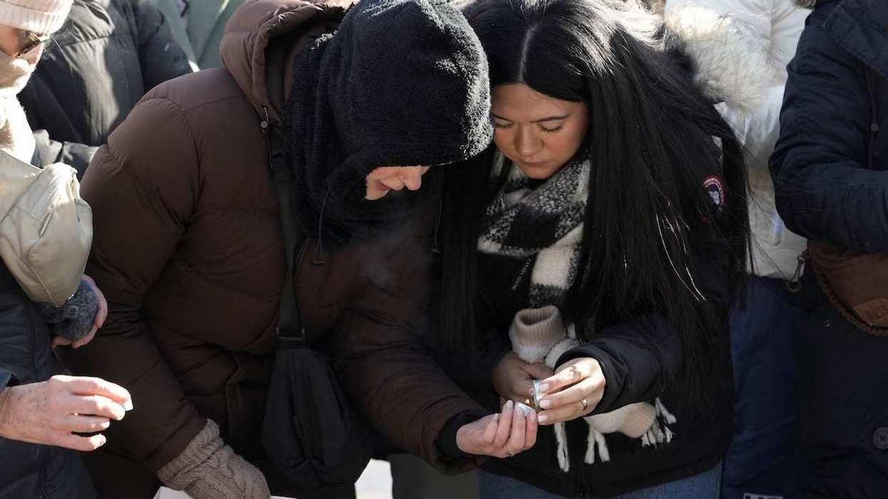 Women light a candle as people gather at a makeshift memorial for Alex Pretti in Minneapolis, Minnesota, USA, on January 25, 2026.