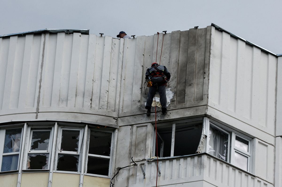 Workers repair damage on the roof of a multi-storey apartment block following a reported drone attack in Moscow, Russia