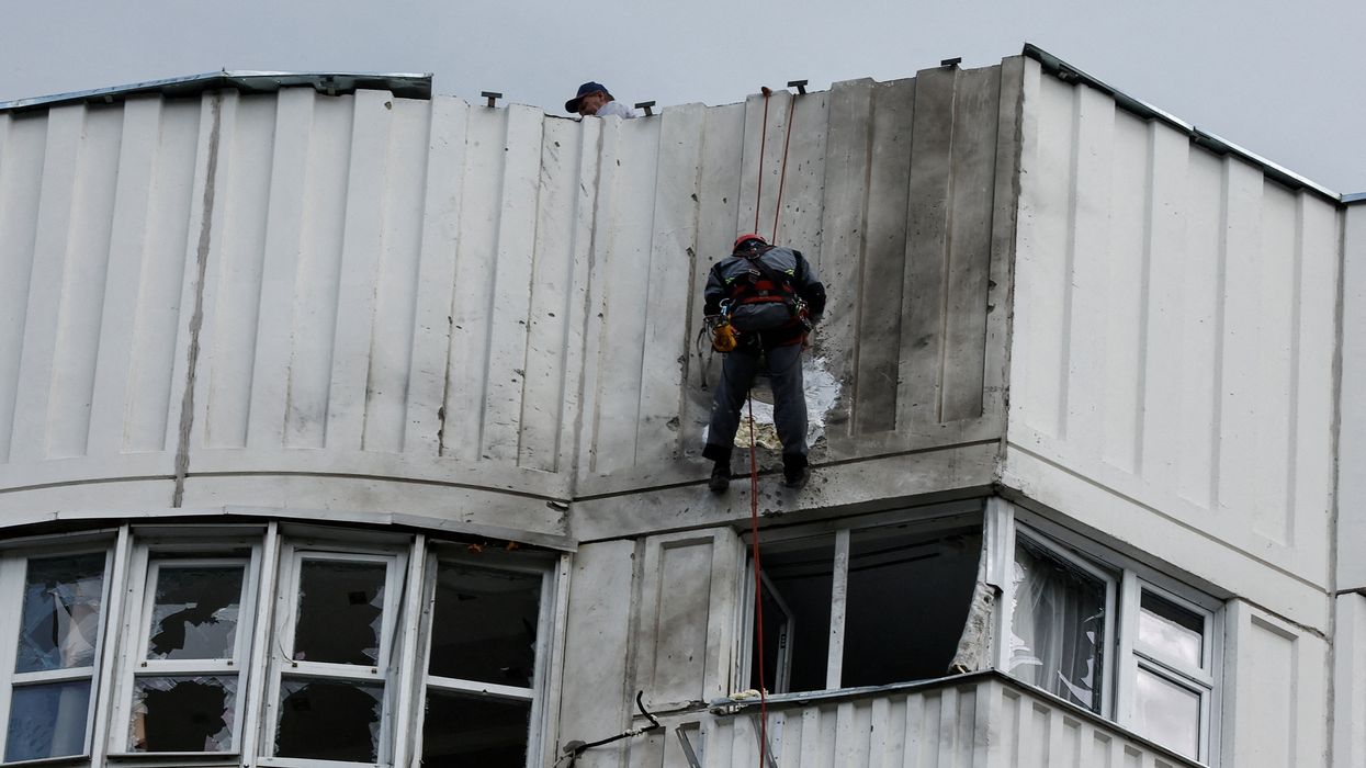 Workers repair damage on the roof of a multi-storey apartment block following a reported drone attack in Moscow, Russia