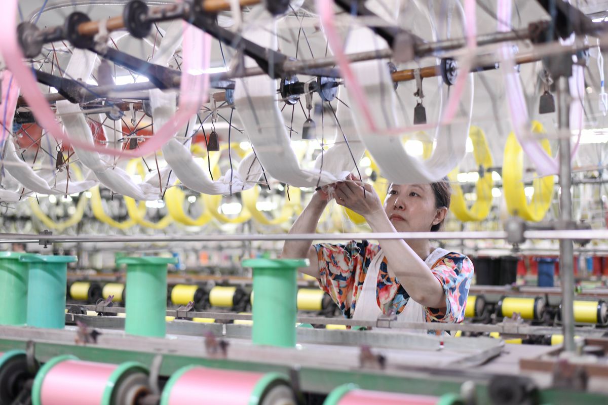 Workers work on a production line at a silk workshop in Haian, Jiangsu province, China.