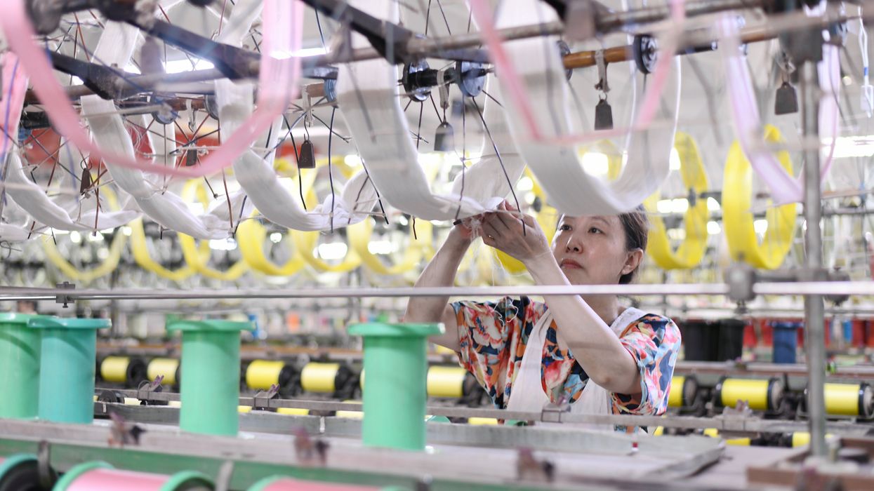 Workers work on a production line at a silk workshop in Haian, Jiangsu province, China.