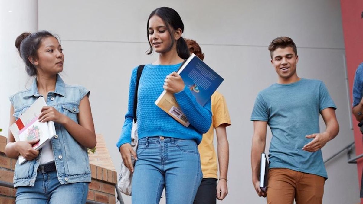 Young adults walking together with books in their hand. 